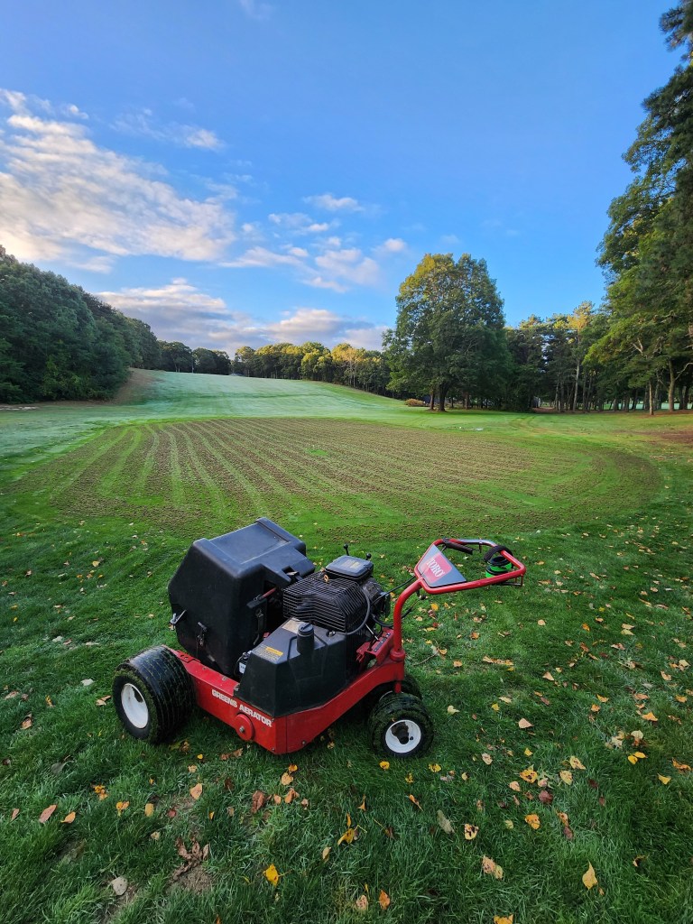 Greens aerator machine on a golf course fairway at dawn